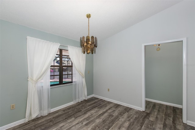 empty room with dark wood-type flooring and a chandelier