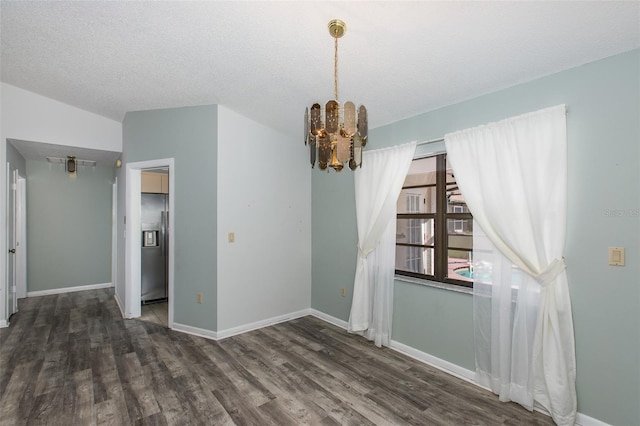 spare room with a textured ceiling, dark hardwood / wood-style flooring, and a notable chandelier