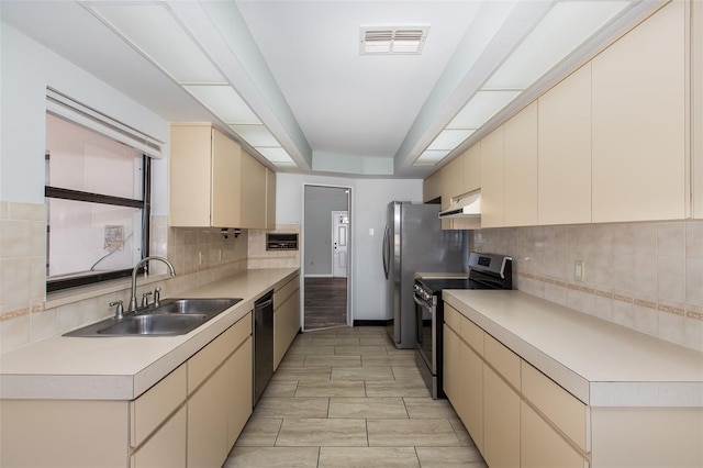 kitchen featuring stainless steel electric range oven, cream cabinets, backsplash, dishwasher, and sink