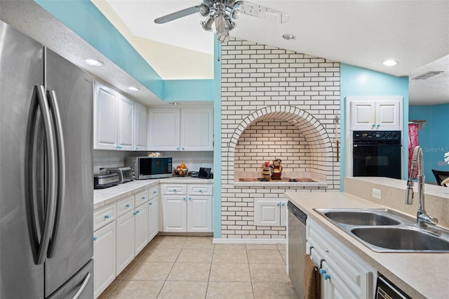 kitchen featuring appliances with stainless steel finishes, tasteful backsplash, vaulted ceiling, sink, and white cabinets