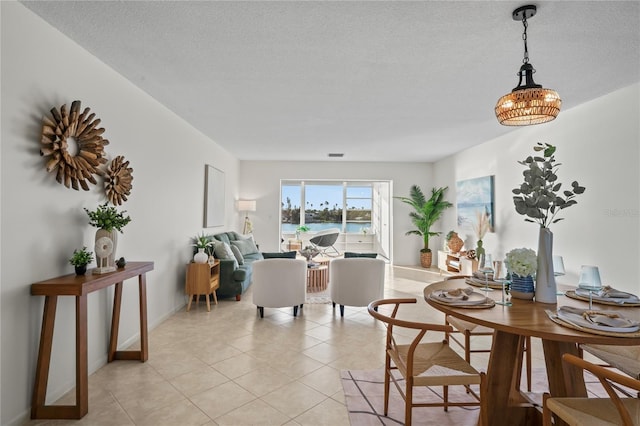 dining area featuring light tile patterned flooring, a textured ceiling, and baseboards