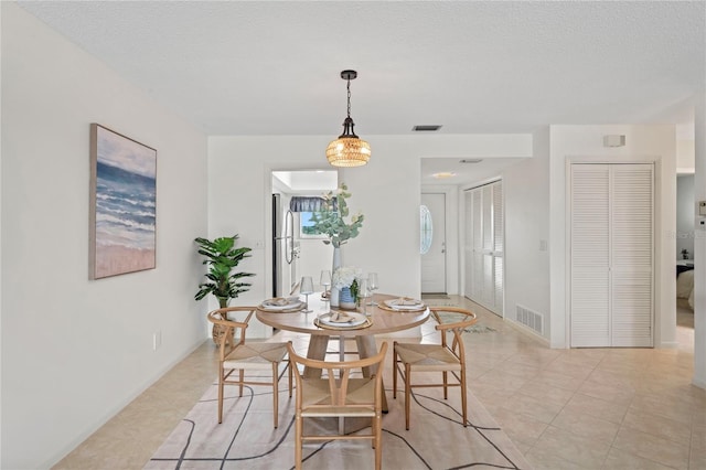 dining room with a textured ceiling, light tile patterned floors, and visible vents