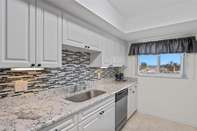 kitchen featuring light tile patterned floors, a sink, white cabinets, dishwasher, and tasteful backsplash