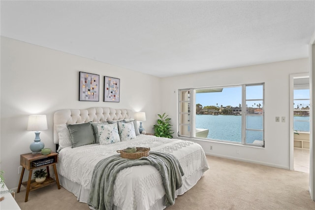 bedroom with light carpet, a water view, and baseboards