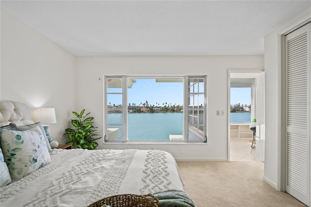 carpeted bedroom with multiple windows, a water view, a closet, and baseboards