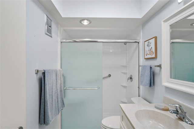 full bathroom featuring toilet, vanity, a shower with door, and visible vents