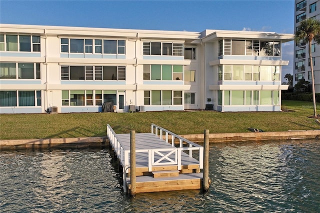 view of dock with a water view, a lawn, and cooling unit