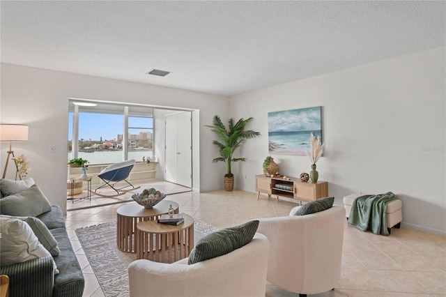 living area with light tile patterned floors, visible vents, and a textured ceiling