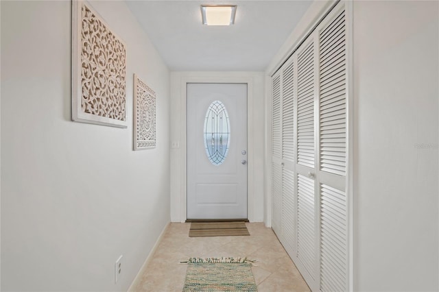 doorway with light tile patterned floors and baseboards