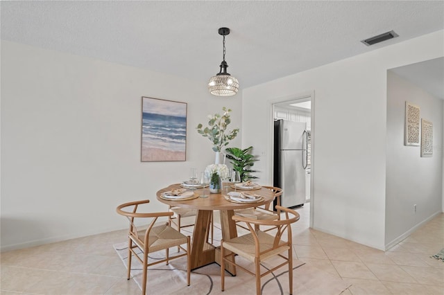 dining space featuring light tile patterned floors, a textured ceiling, visible vents, and baseboards