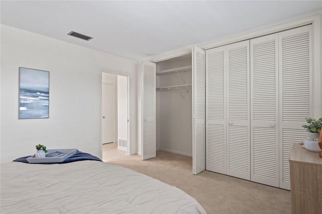 bedroom featuring light carpet, visible vents, and multiple closets