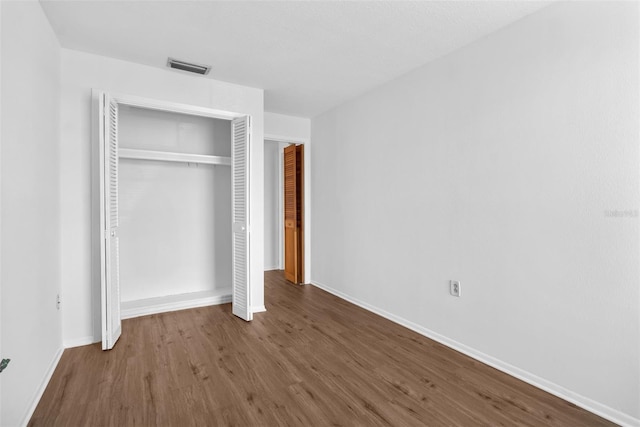 unfurnished bedroom featuring a closet and dark wood-type flooring