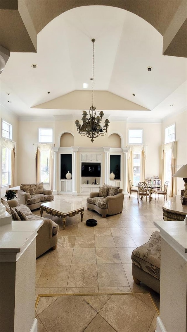 living room featuring an inviting chandelier, a high ceiling, light tile floors, and ornate columns