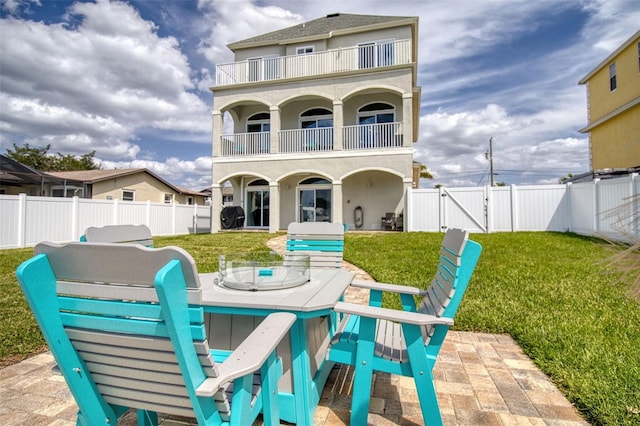 rear view of property with a lawn, a patio area, and a balcony