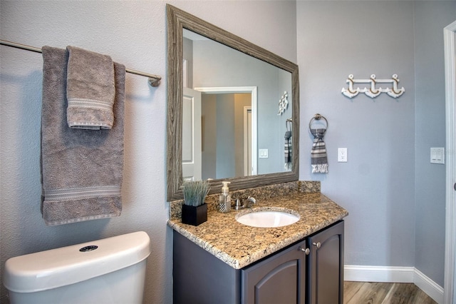 bathroom with hardwood / wood-style flooring, vanity, and toilet