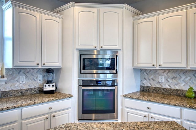 kitchen featuring white cabinetry, stainless steel microwave, and backsplash