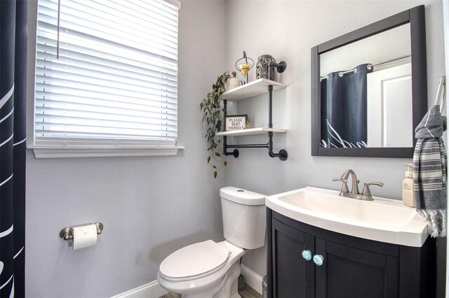 bathroom with toilet, baseboards, and vanity