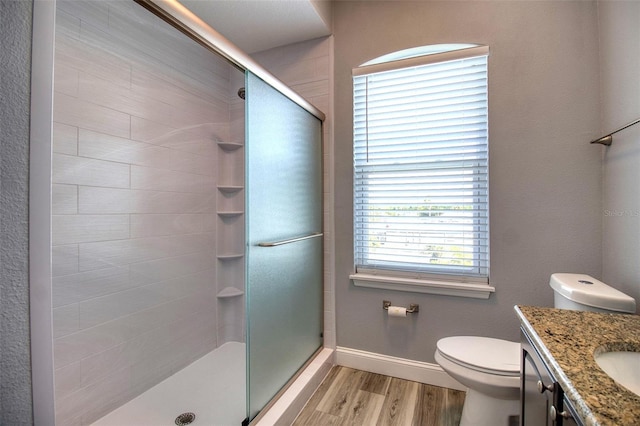 bathroom with a stall shower, wood finished floors, vanity, and baseboards