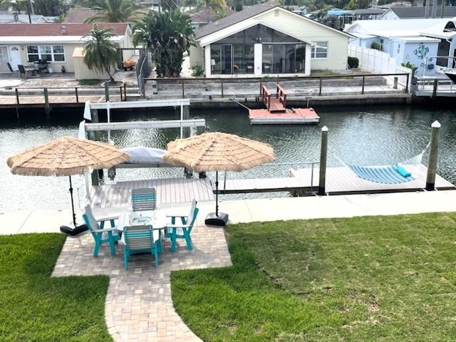 view of swimming pool featuring a yard, a water view, a patio area, fence, and a dock