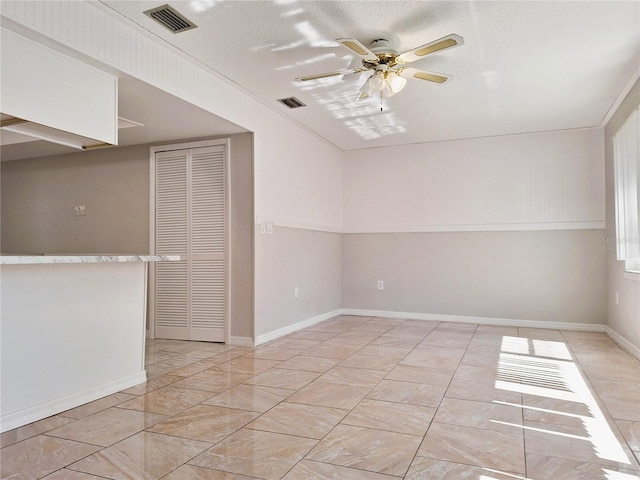 unfurnished room with baseboards, a textured ceiling, visible vents, and a ceiling fan