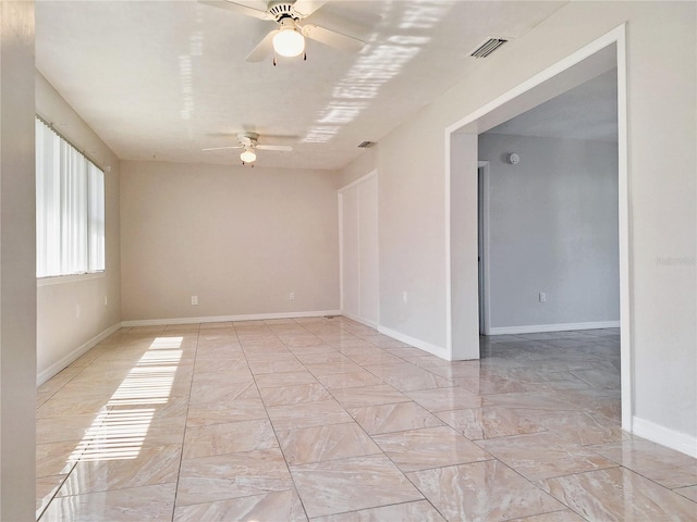 spare room featuring visible vents, ceiling fan, and baseboards