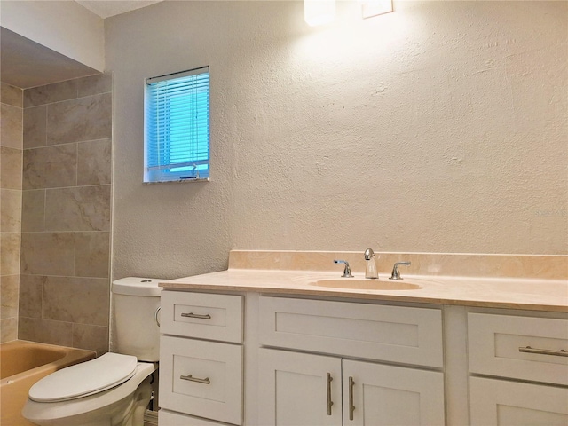 full bathroom with toilet, vanity, and a textured wall