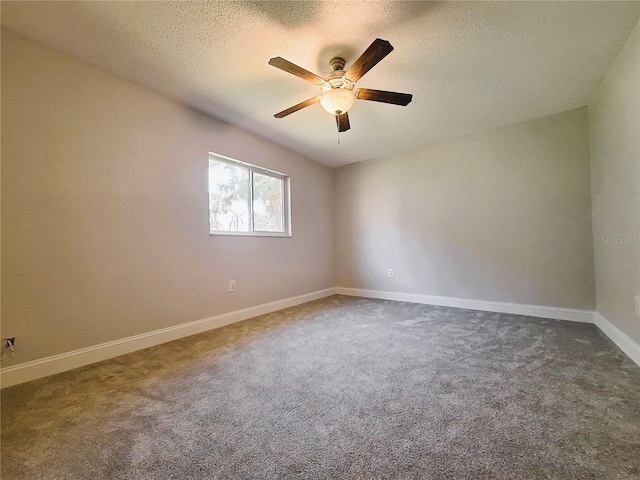 empty room featuring a ceiling fan, baseboards, dark carpet, and a textured ceiling