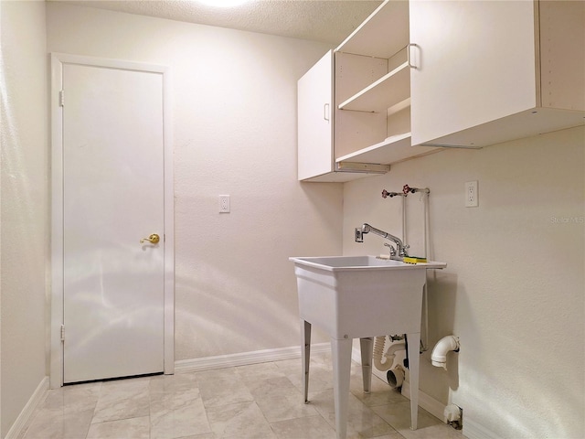 clothes washing area featuring a textured ceiling, laundry area, washer hookup, and baseboards