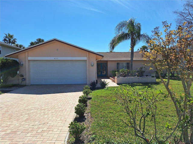 single story home featuring an attached garage, a front yard, decorative driveway, and stucco siding