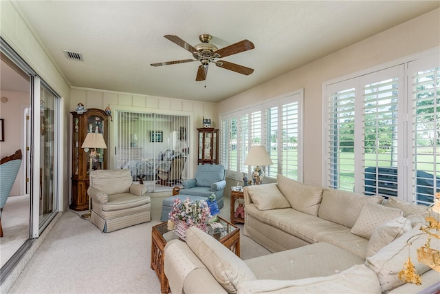 living room featuring plenty of natural light, light colored carpet, and ceiling fan