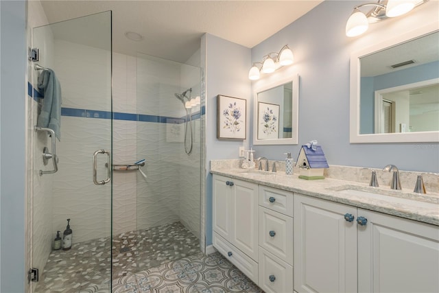 bathroom with a shower with door, large vanity, double sink, and tile flooring