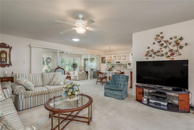 living room with a textured ceiling, light colored carpet, and ceiling fan with notable chandelier