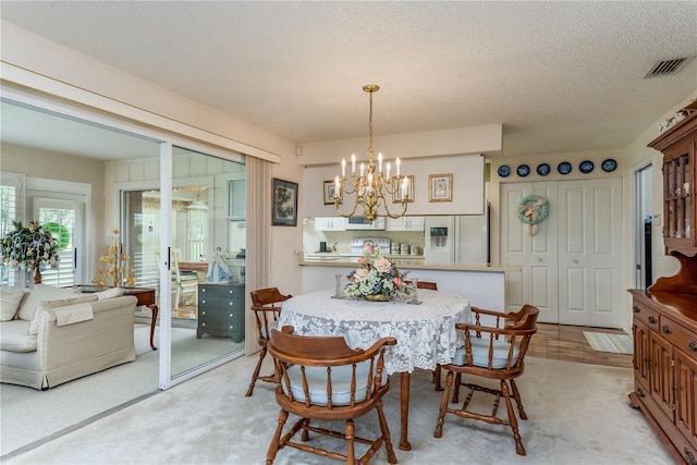 carpeted dining space with an inviting chandelier and a textured ceiling