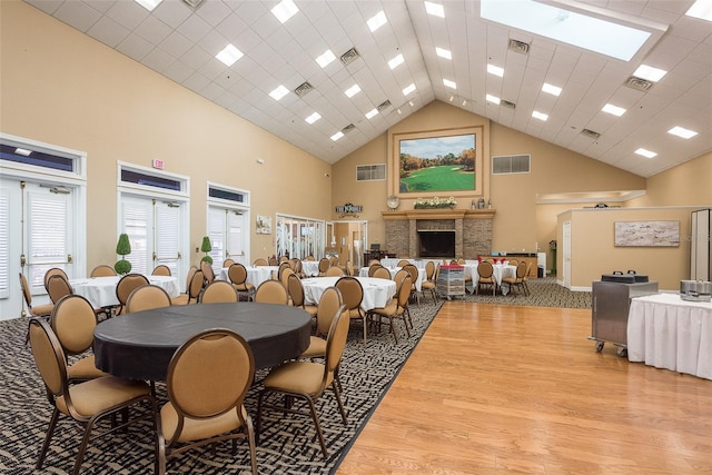 dining space with a skylight, high vaulted ceiling, and light wood-type flooring