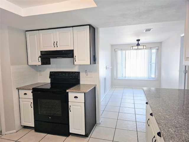 kitchen with light tile patterned floors, black / electric stove, white cabinets, and tasteful backsplash