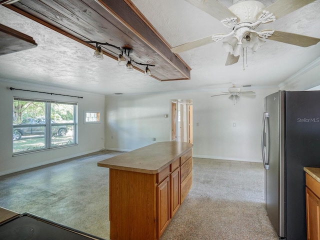 kitchen with ceiling fan, a kitchen island, a textured ceiling, and stainless steel fridge