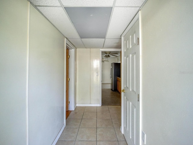 corridor featuring light tile floors and a drop ceiling