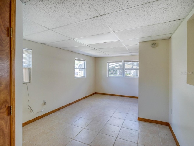 unfurnished room with a drop ceiling and light tile floors