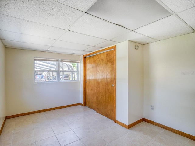 tiled empty room featuring a drop ceiling