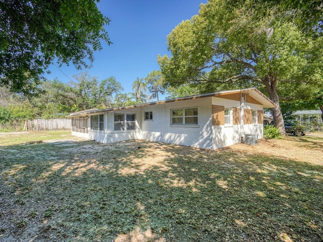 back of property with a lawn and central AC