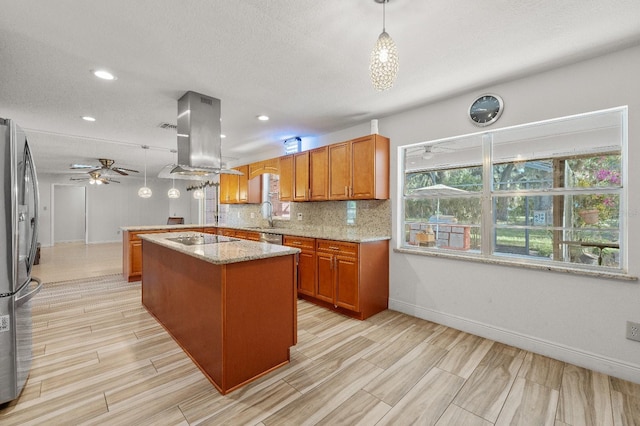 kitchen featuring light stone counters, ceiling fan, backsplash, decorative light fixtures, and island exhaust hood