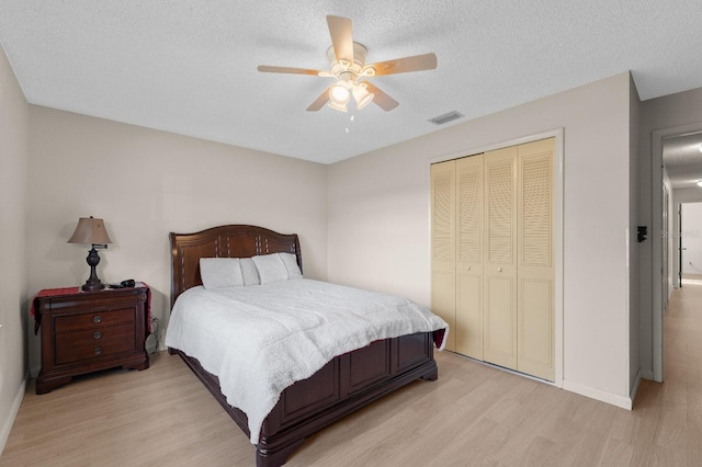 bedroom featuring a closet, light hardwood / wood-style floors, ceiling fan, and a textured ceiling