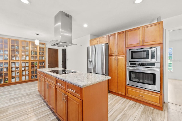 kitchen featuring island range hood, stainless steel appliances, a center island, decorative light fixtures, and light stone countertops