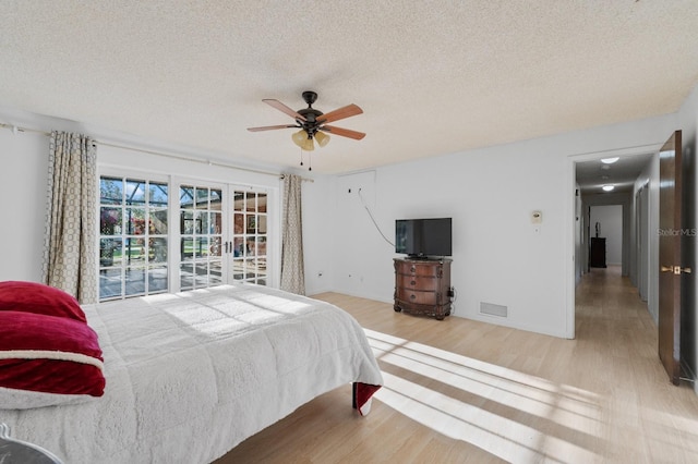 bedroom with ceiling fan, a textured ceiling, light wood-type flooring, and access to outside