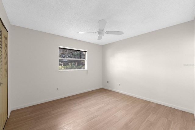 spare room featuring ceiling fan, light hardwood / wood-style flooring, and a textured ceiling