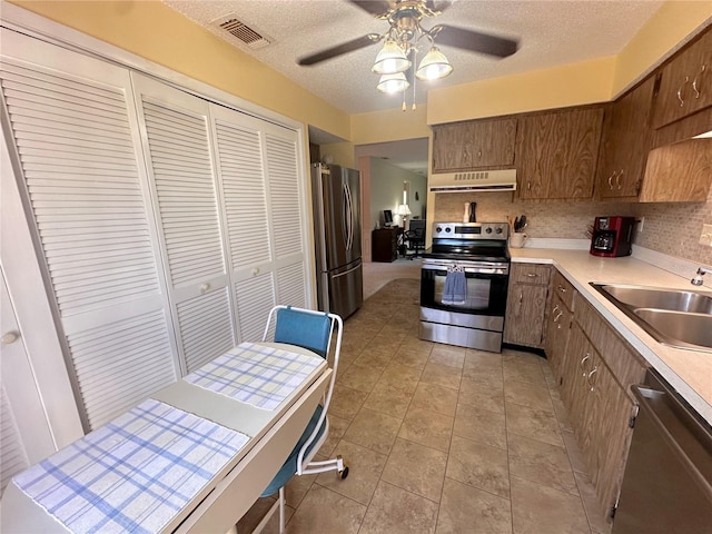 kitchen with stainless steel appliances, ceiling fan, sink, tasteful backsplash, and light tile patterned flooring