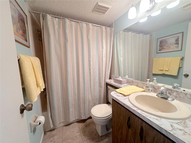 bathroom featuring a textured ceiling, vanity, tile patterned flooring, and toilet