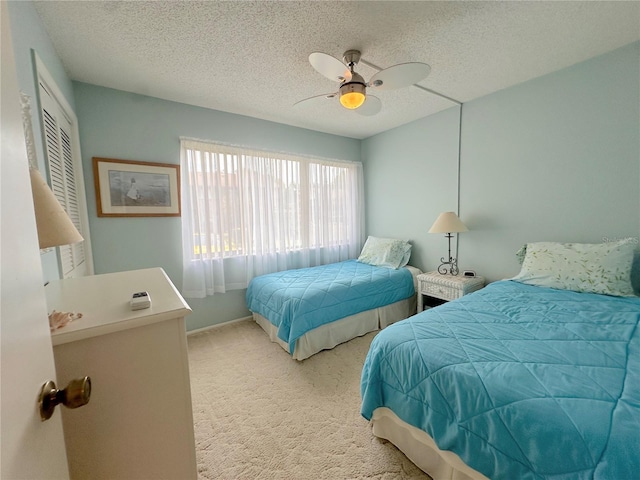 bedroom with ceiling fan, a textured ceiling, and light colored carpet