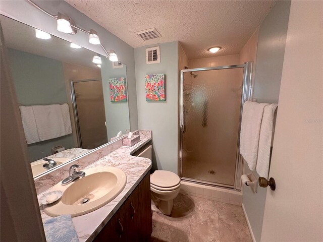 bathroom with a textured ceiling, toilet, tile patterned flooring, walk in shower, and vanity