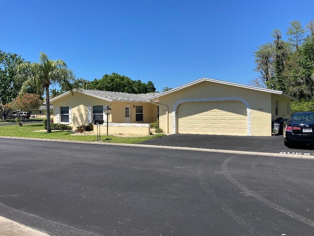 ranch-style home featuring a garage, aphalt driveway, and stucco siding